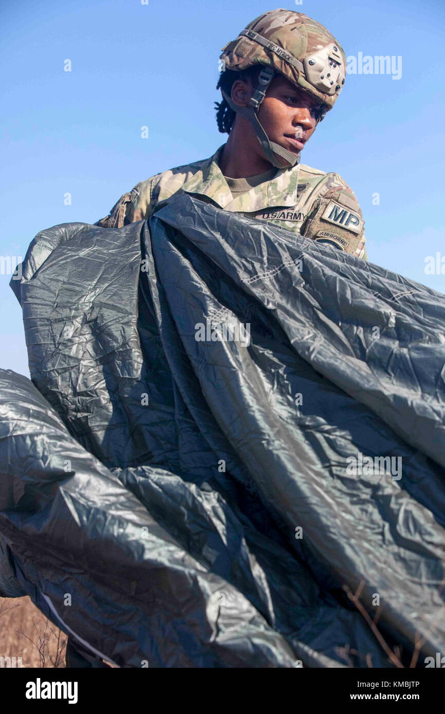 U.S. Army Sgt. 1st Class Tiffany Myrick, 21st Military Police Company, to recovers her parchute on Sicily Drop Zone during the 20th Annual Randy Oler Memorial Operation Toy Drop, at Fort Bragg, North Carolina, Dec. 01, 2017. This year, eight countries are participating and they include; Colombia, Canada, Latvia, the Netherlands, Sweden, Italy, Germany, and Poland. Operation Toy Drop, hosted by the U.S. Army Civil Affairs & Psychological Operations Command (Airborne) is the largest combined airborne operation conducted worldwide.  The event allows Soldiers the opportunity to train on their mili Stock Photo