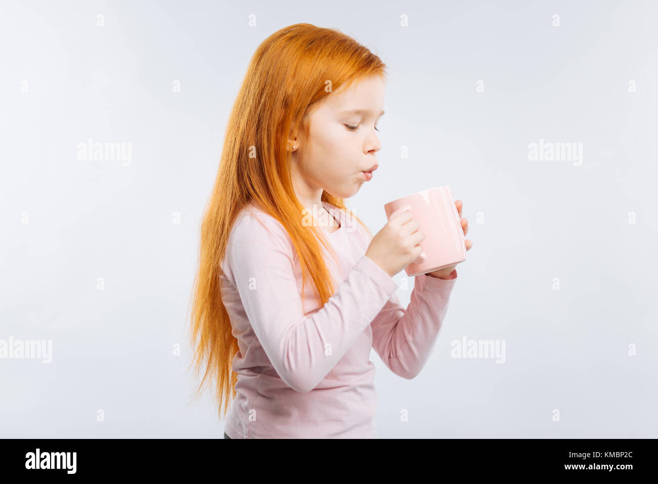Careful kid blowing at cup Stock Photo - Alamy