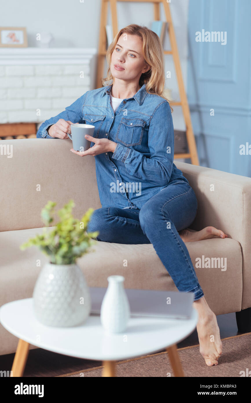 Calm young woman sitting on a sofa and holding a mug Stock Photo - Alamy