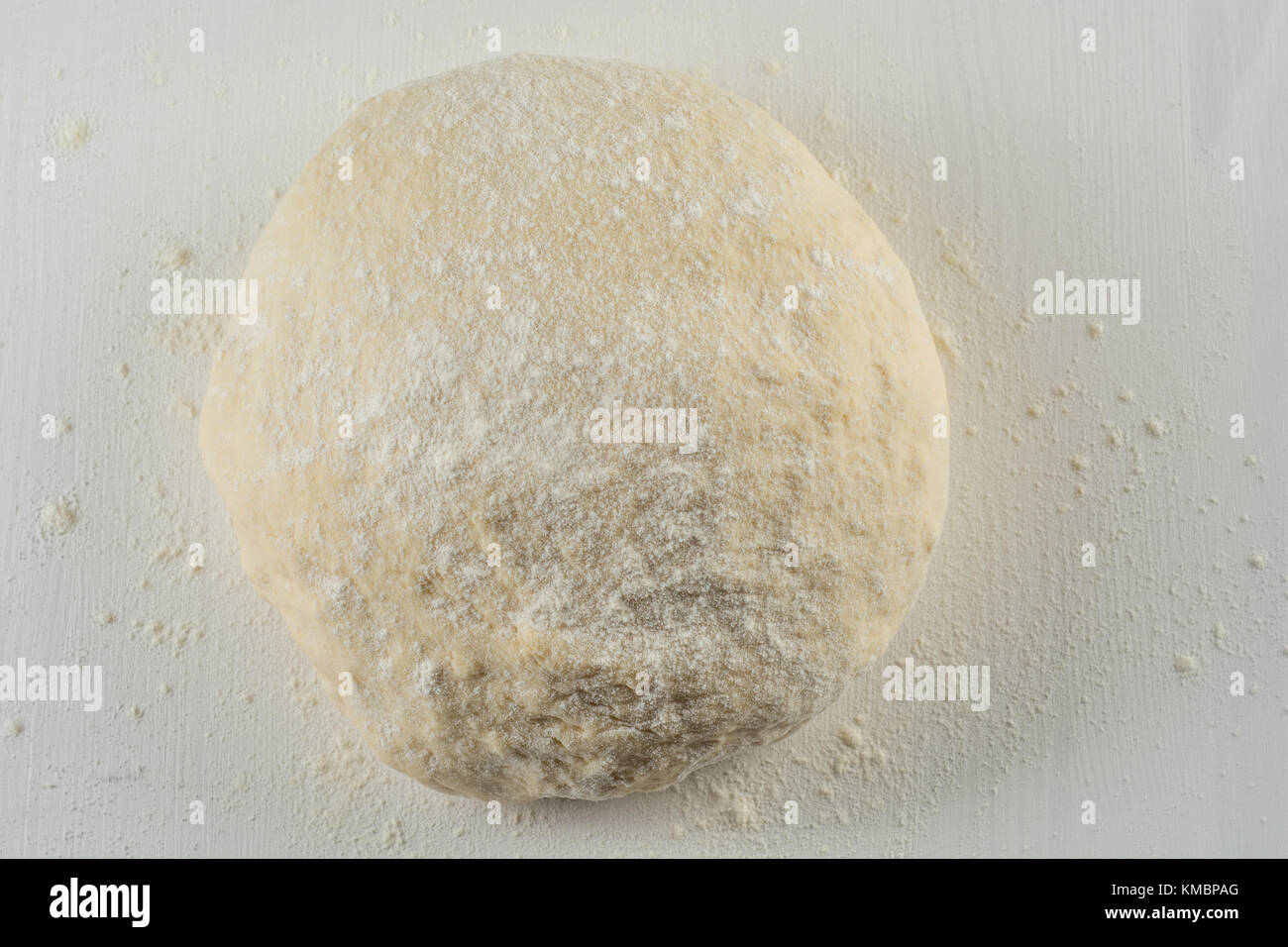 Ball of pizza dough on a wooden background with dusting of flour Stock
