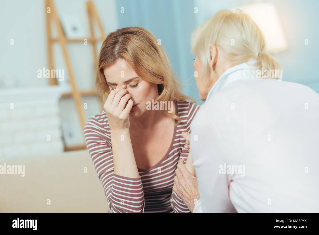 Tired ill woman closing her eyes and touching her nose Stock Photo