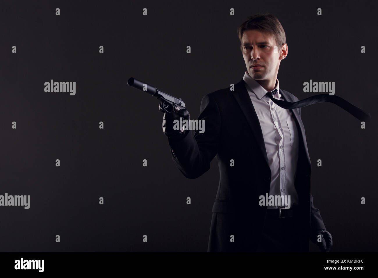 Portrait of man in leather gloves with gun isolated on black background. Stock Photo