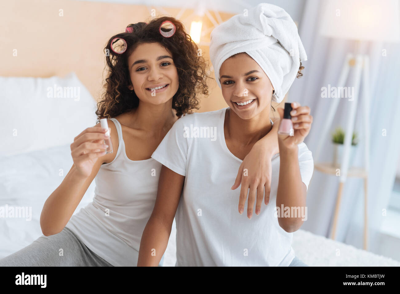 Stylish girls posing with nail polishes at home Stock Photo