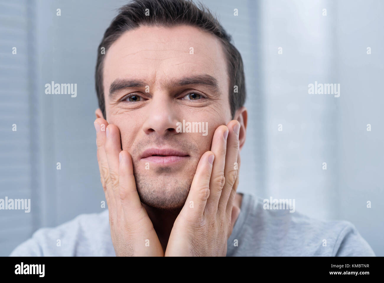 Young handsome man moisturizing his skin Stock Photo