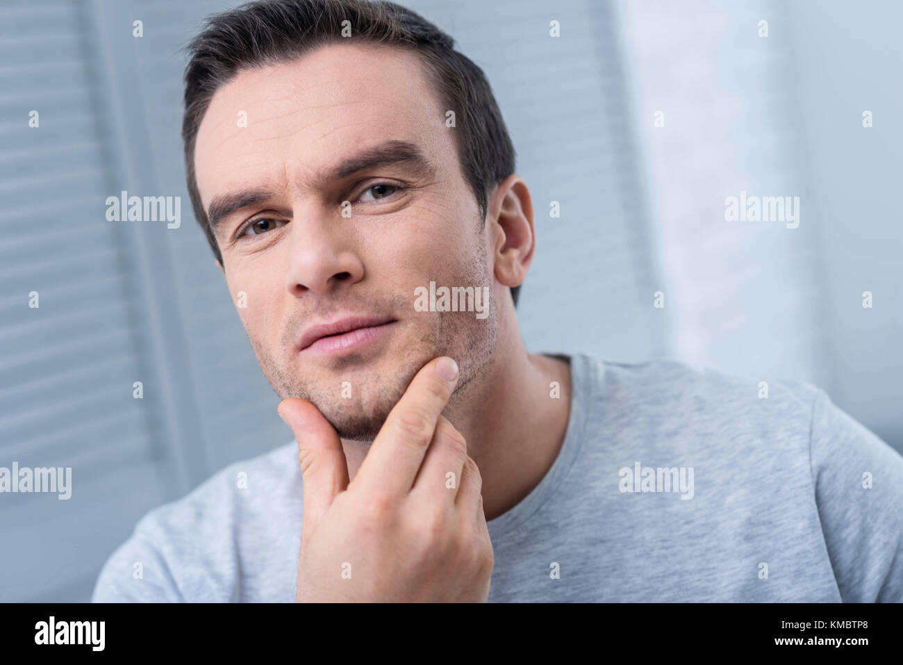 Thoughtful earnest man admiring his bristles Stock Photo