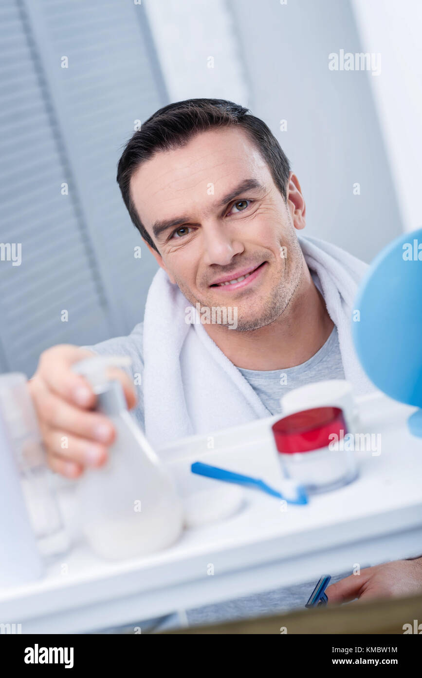 Vigorous energetic man  applying lotion  Stock Photo