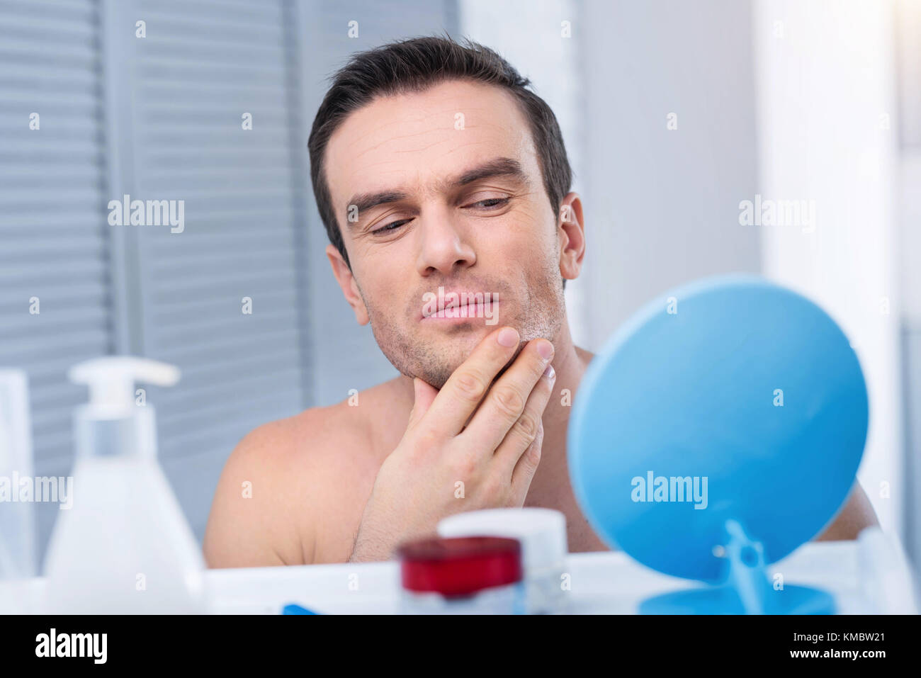 Handsome concentrated man examining his face Stock Photo