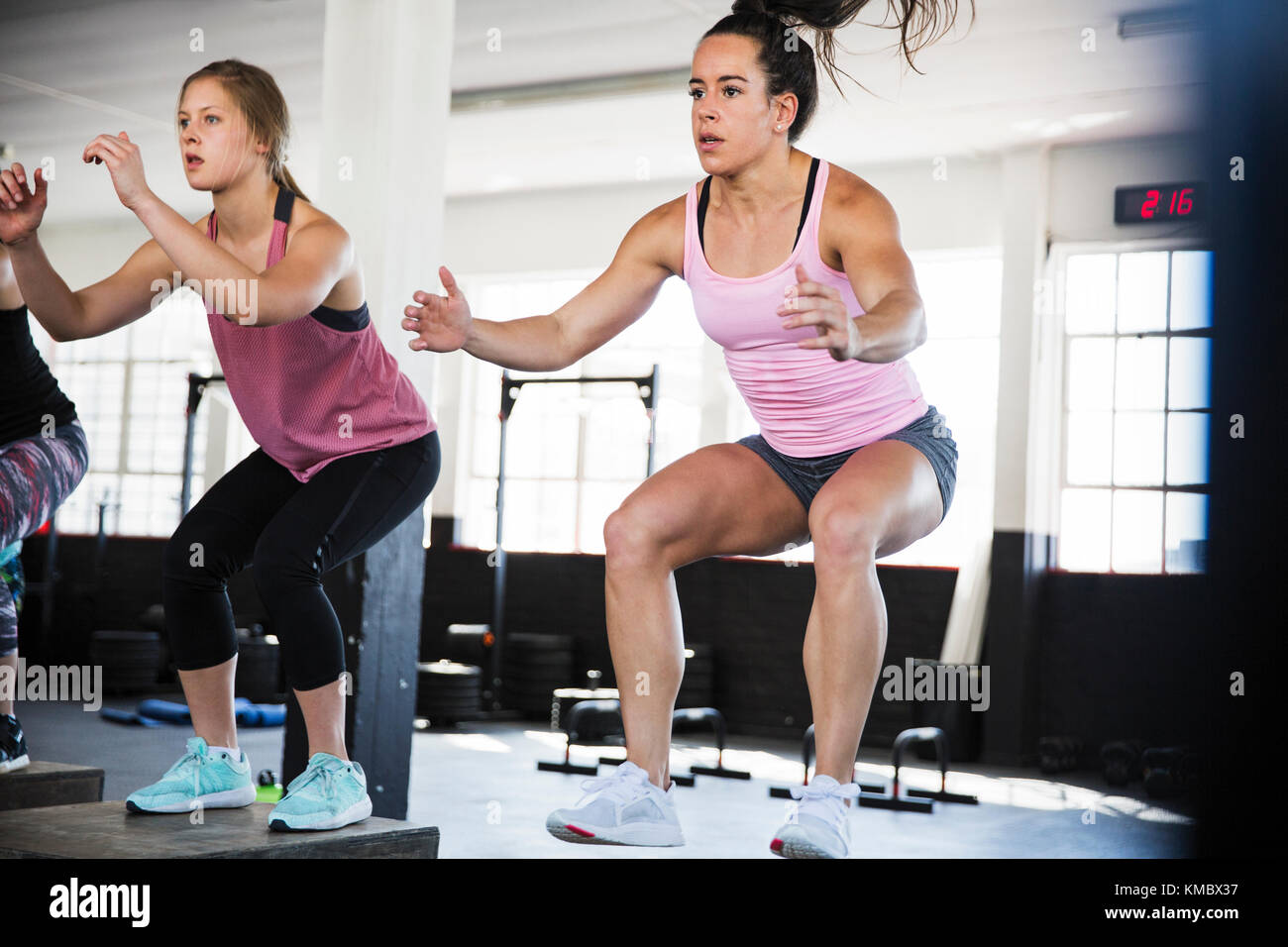 Determined young women doing jump squats in exercise class Stock Photo