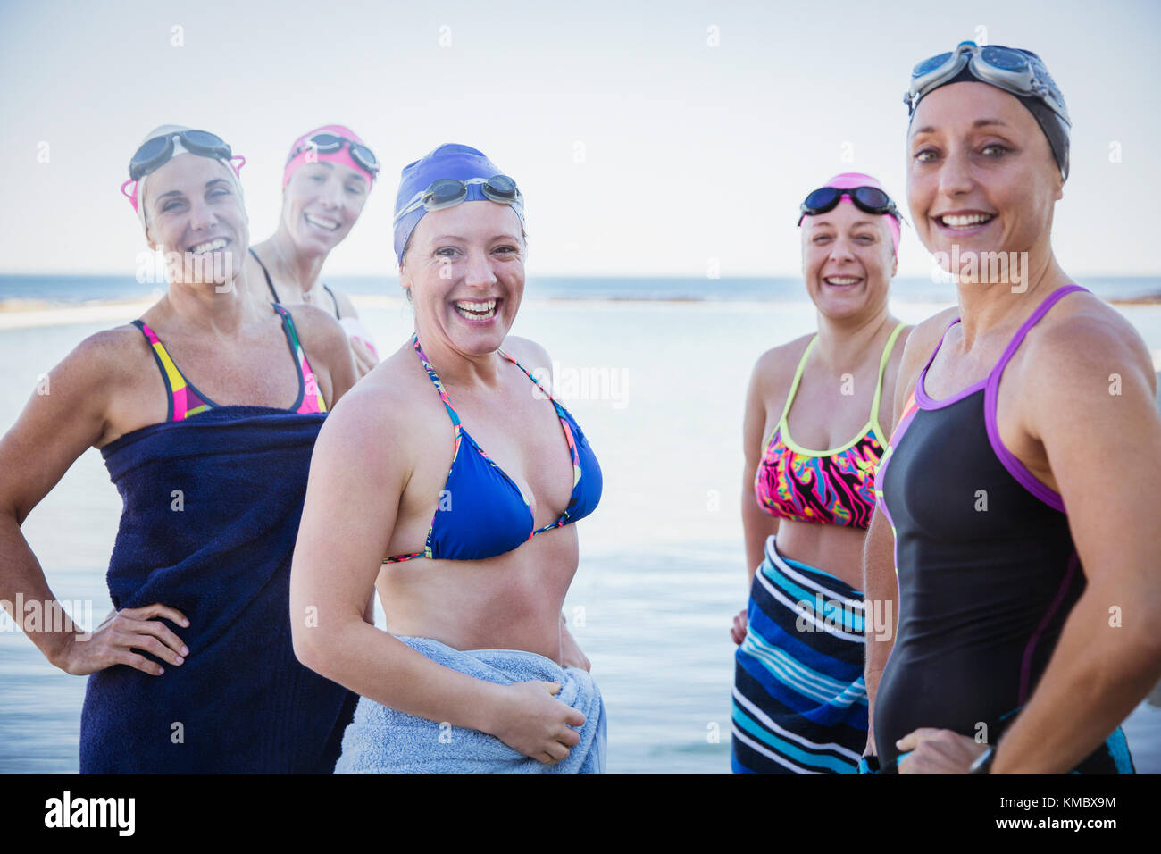 Portrait smiling, confident female open water swimmers drying off with towels at ocean Stock