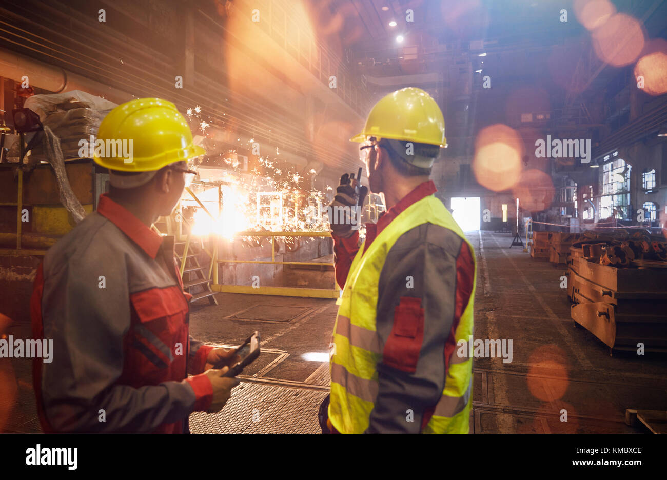 Steelworkers with walkie-talkie watching welding in steel mill Stock ...