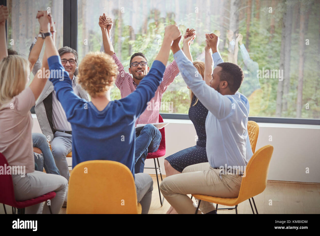 People holding hands in circle in group therapy session Stock Photo
