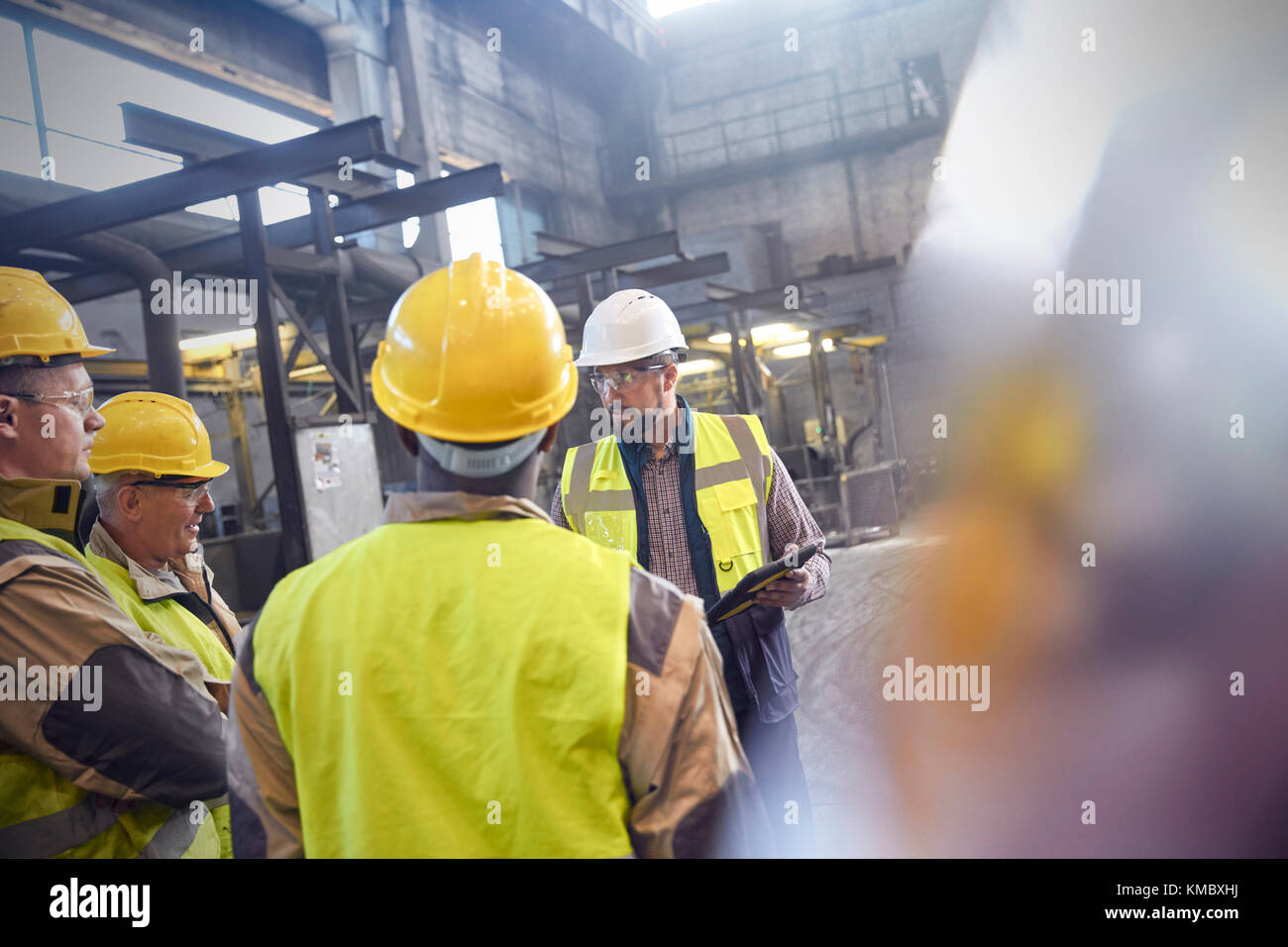 Supervisor and steelworkers talking in meeting in steel mill Stock