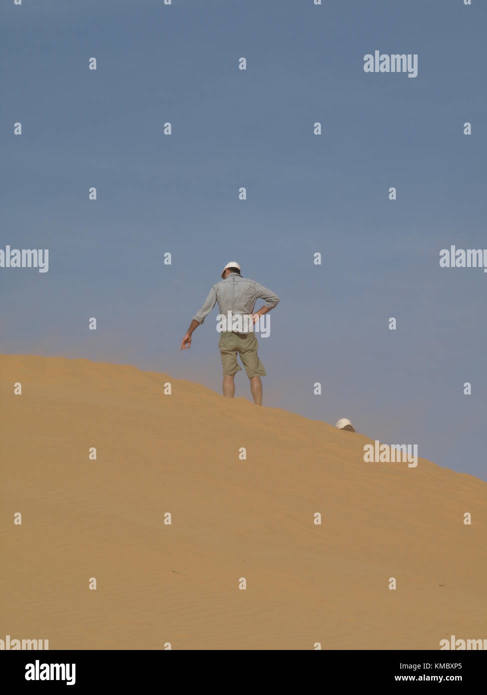 a man standing on sand dune and pointing down with his hand Stock Photo