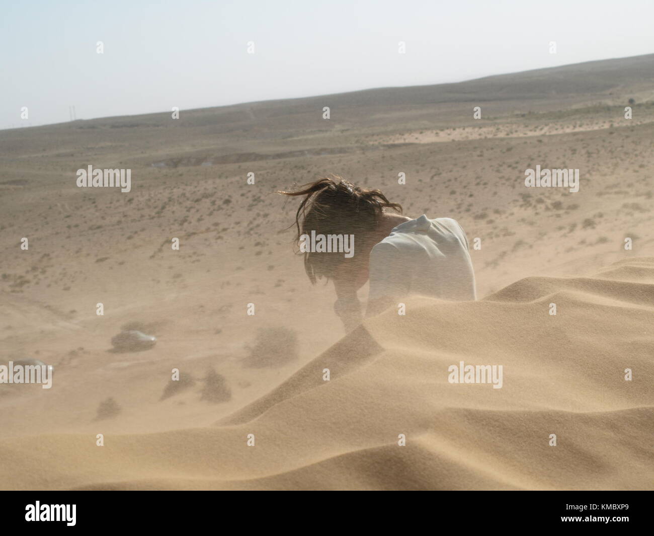 girl covering her face from sand storm in the desert Stock Photo