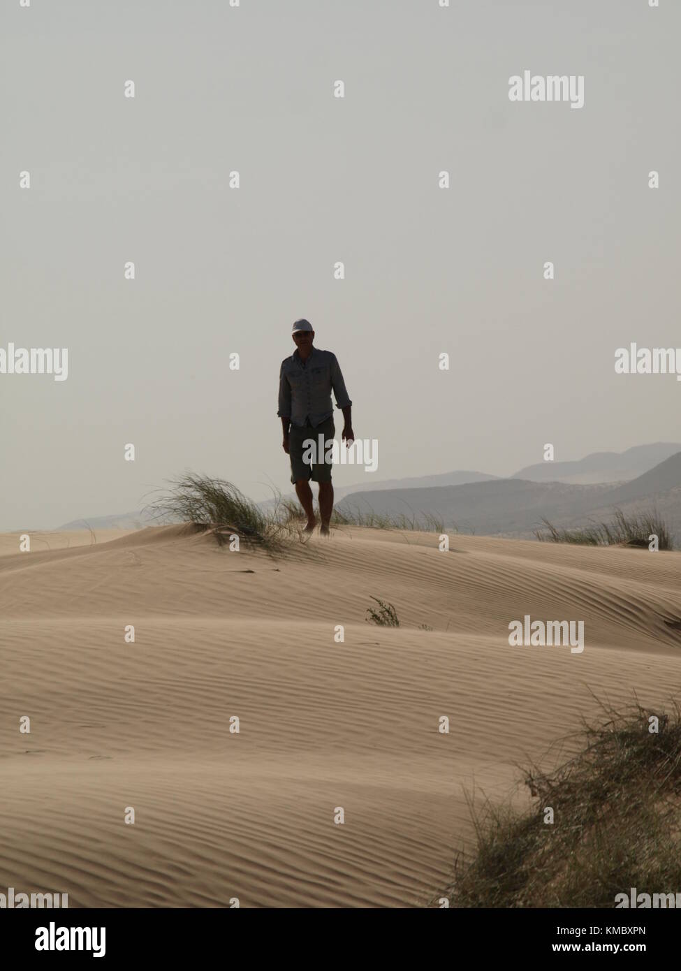 a man walking in the desert on a sand dune Stock Photo