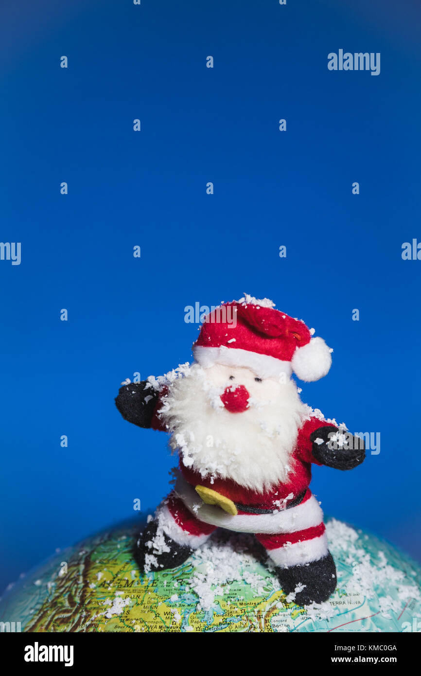 Santa Claus surfing over world globe with snow. Stock Photo