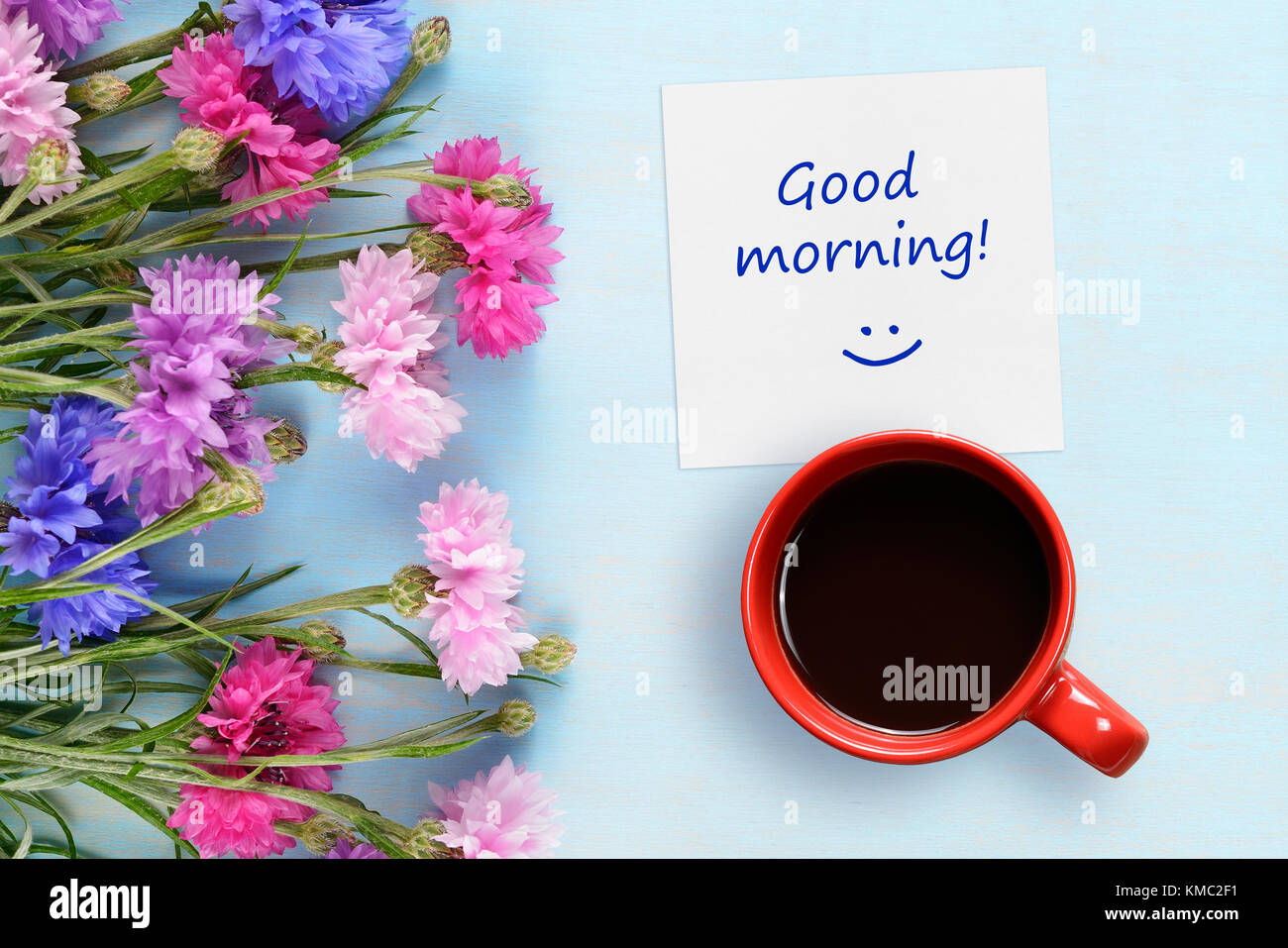 Good morning wishes, coffee cup and cornflowers on blue background ...