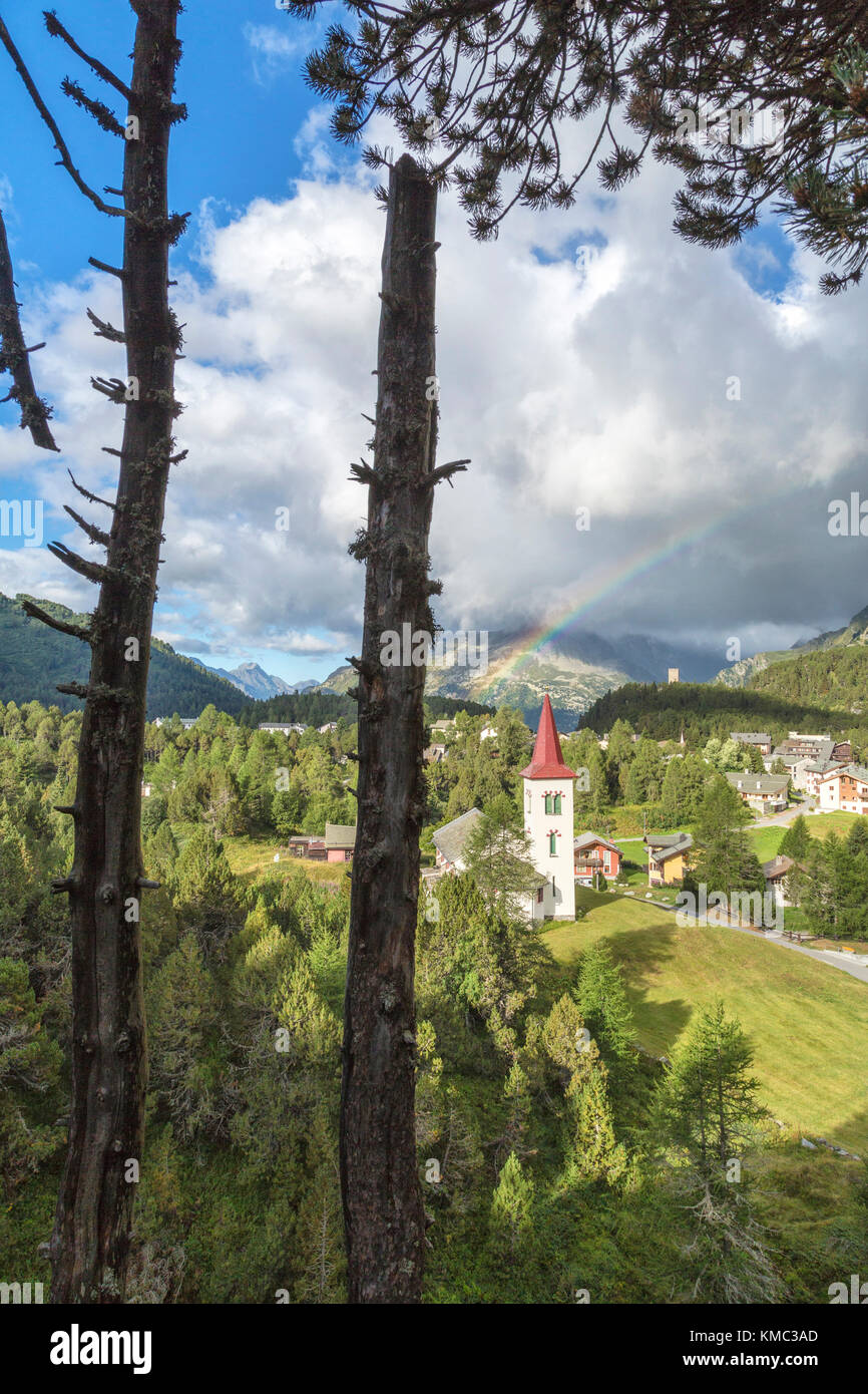 Rainbow over Chiesa Bianca and the village of Maloja, Bregaglia Valley, Canton of Graubunden, Engadin, Switzerland Stock Photo