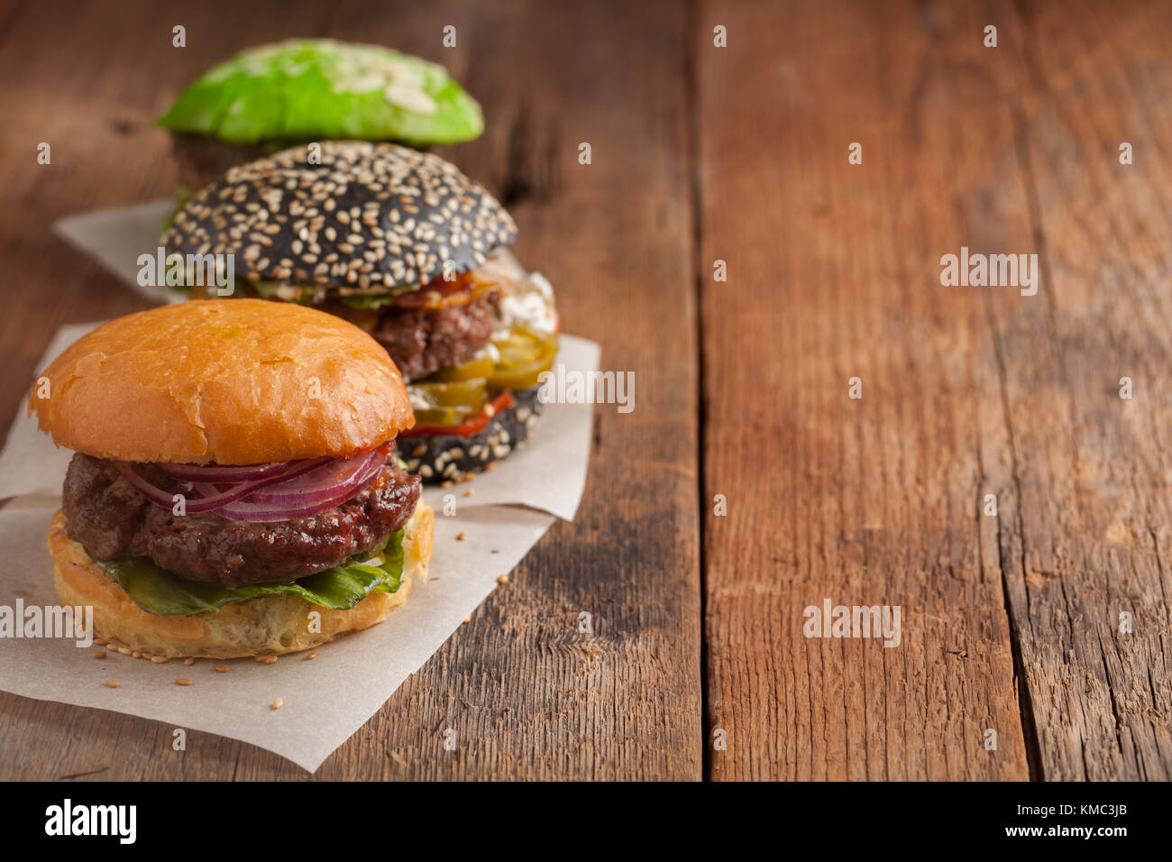 Set of three mini homemade Burger with marble beef and vegetables on a old wooden background. the concept of junk food and fast food. with copy space. Stock Photo