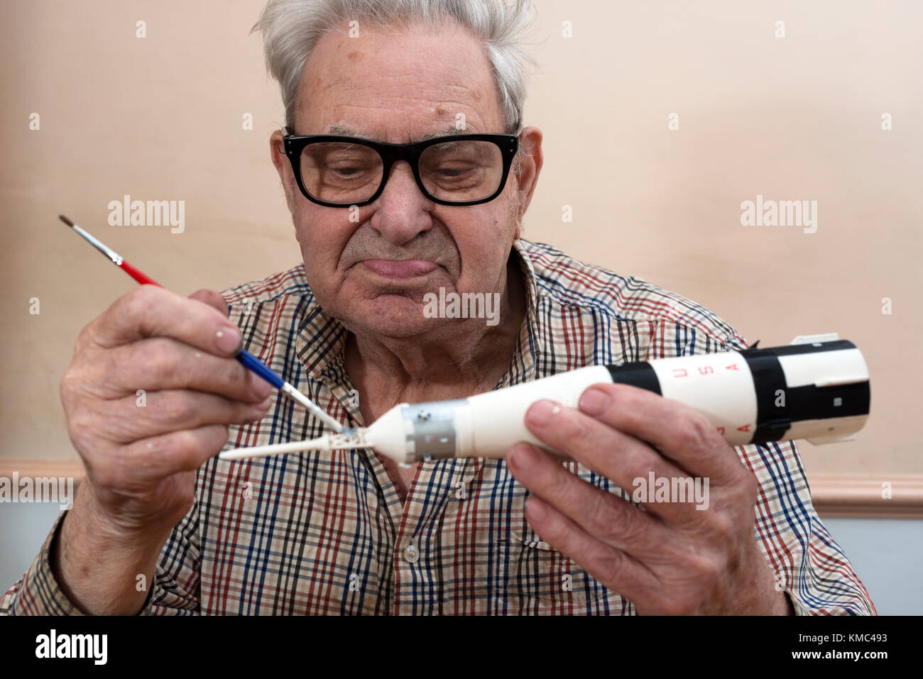 Elderly man making a Airfix model of the Apollo 7 space rocket Stock Photo