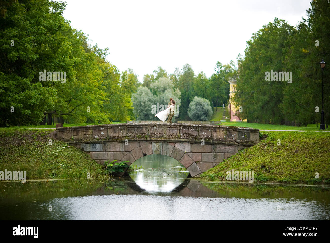 Happy bride and groom embrace and kiss on the bridge Stock Photo - Alamy