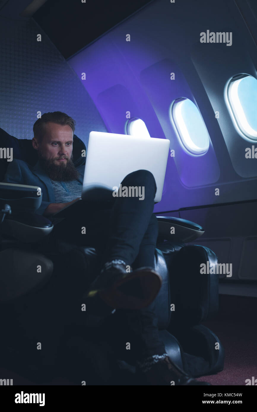Businessman using laptop in airplane Stock Photo Alamy