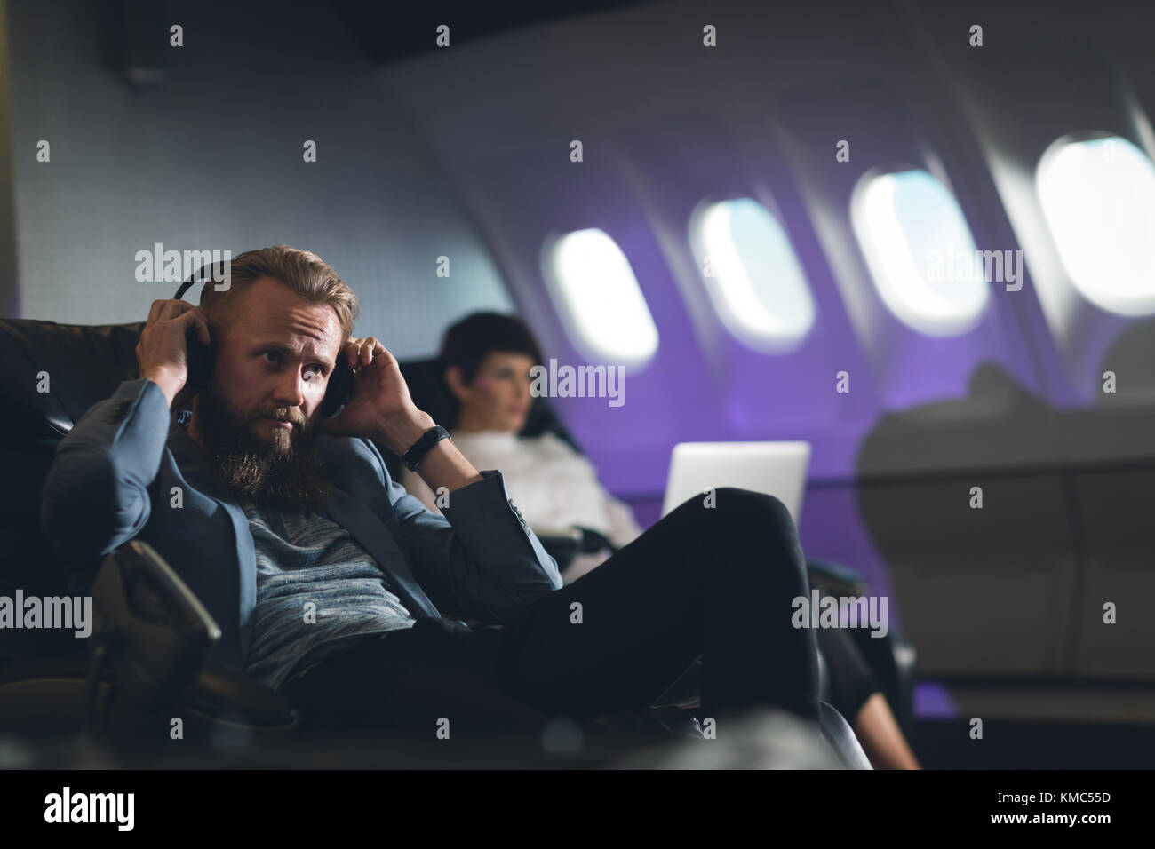 Businessman wearing headphones in airplane Stock Photo Alamy