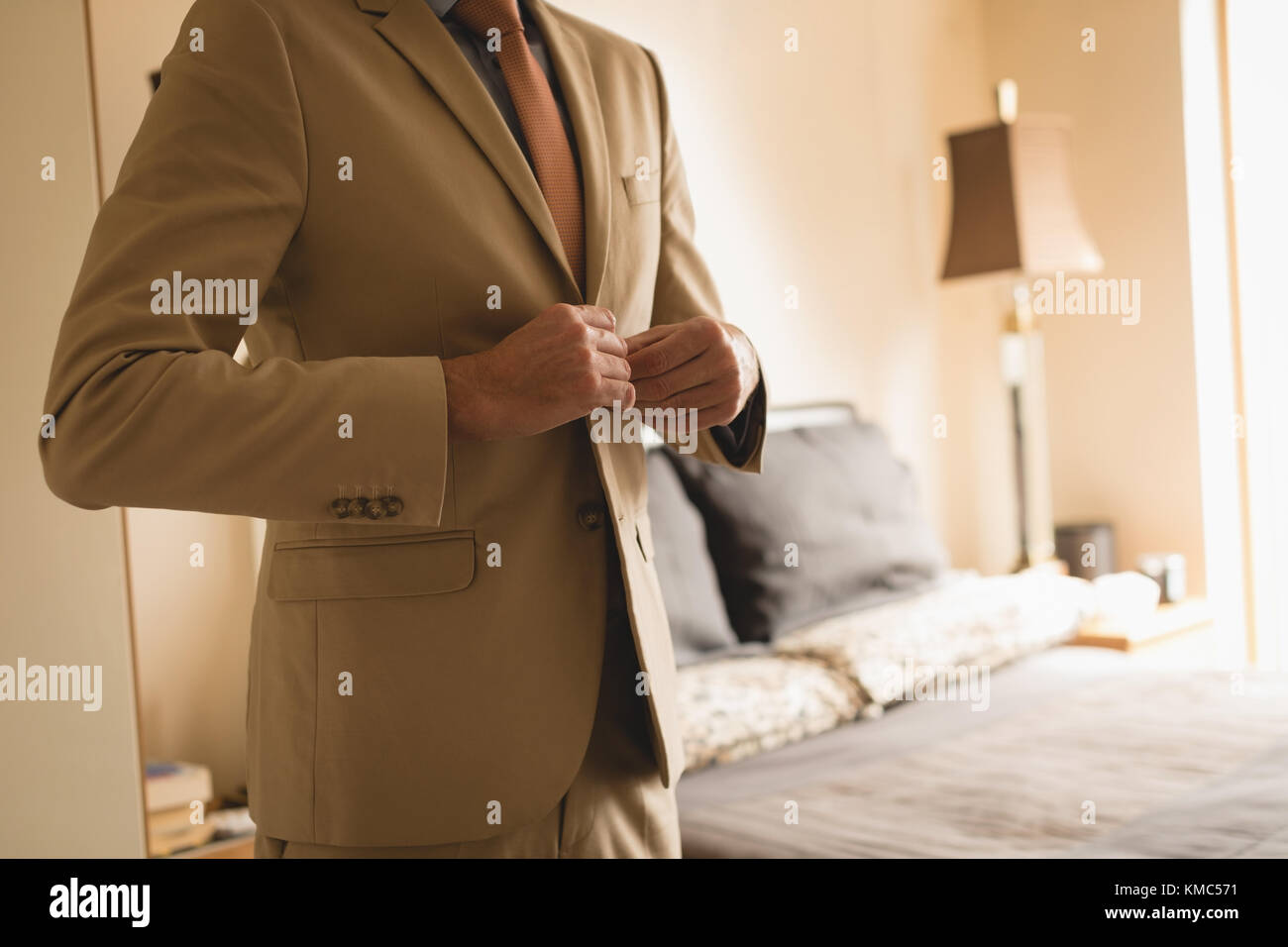 Man wearing his blazer in bedroom Stock Photo