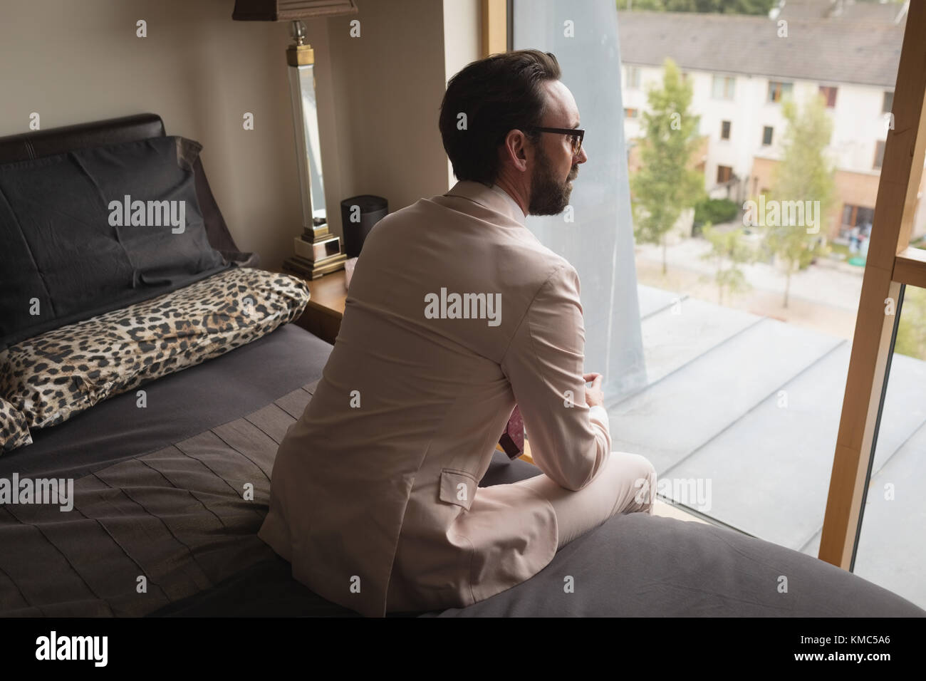 Man in full suit sitting on bedroom Stock Photo