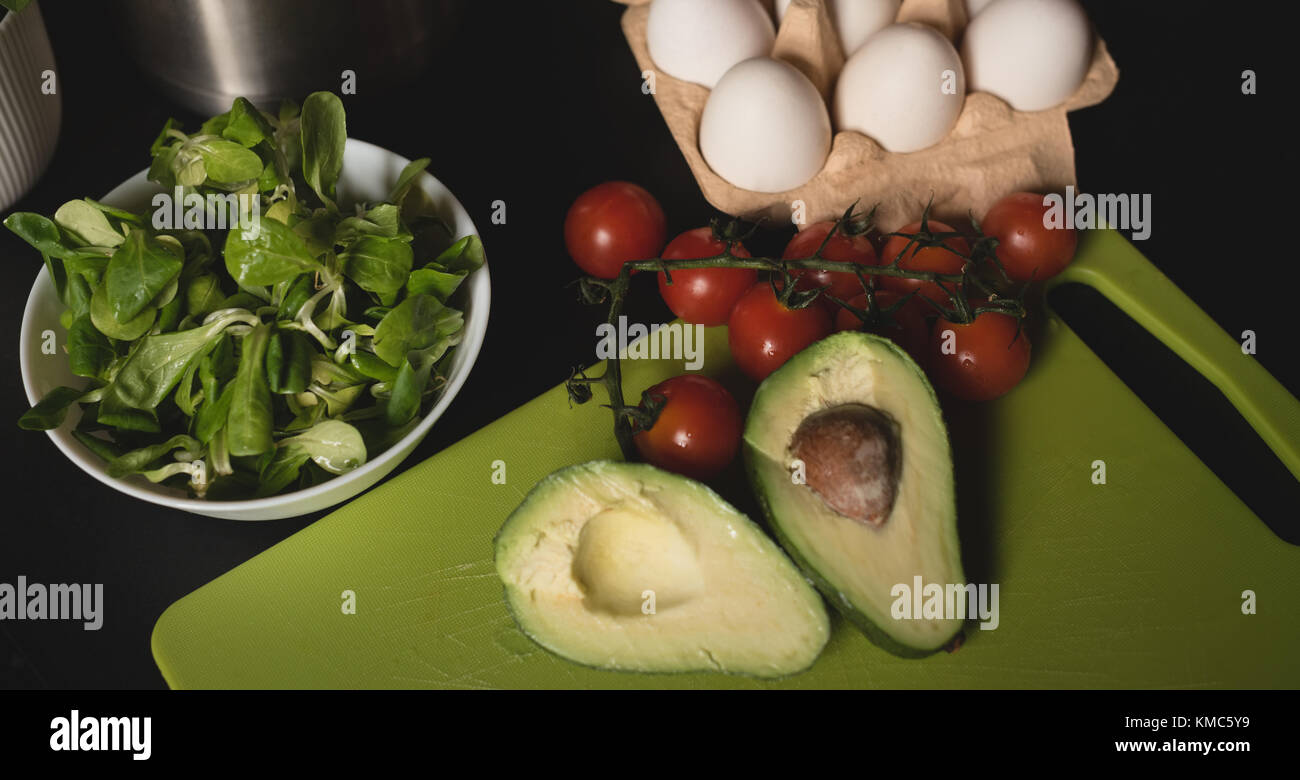 Leafy vegetable in bowl with avocado, cherry tomato and egg carton Stock Photo
