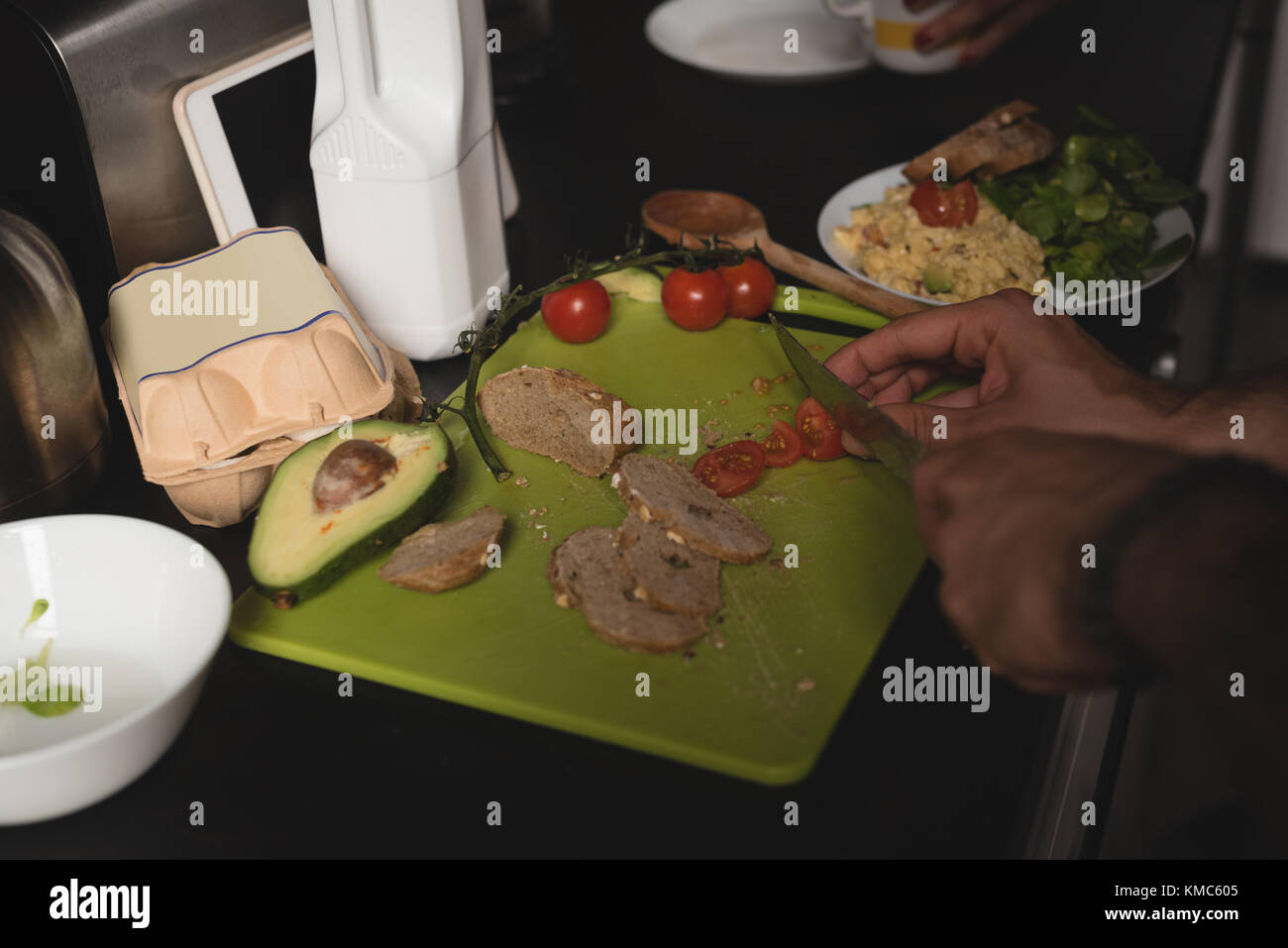 Man chopping cherry tomato on chopping board in kitchen Stock Photo - Alamy