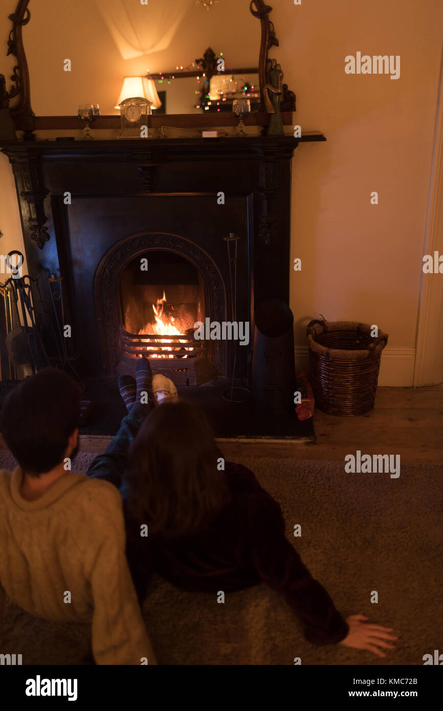 Couple sitting on carpet in front of fireplace Stock Photo Alamy