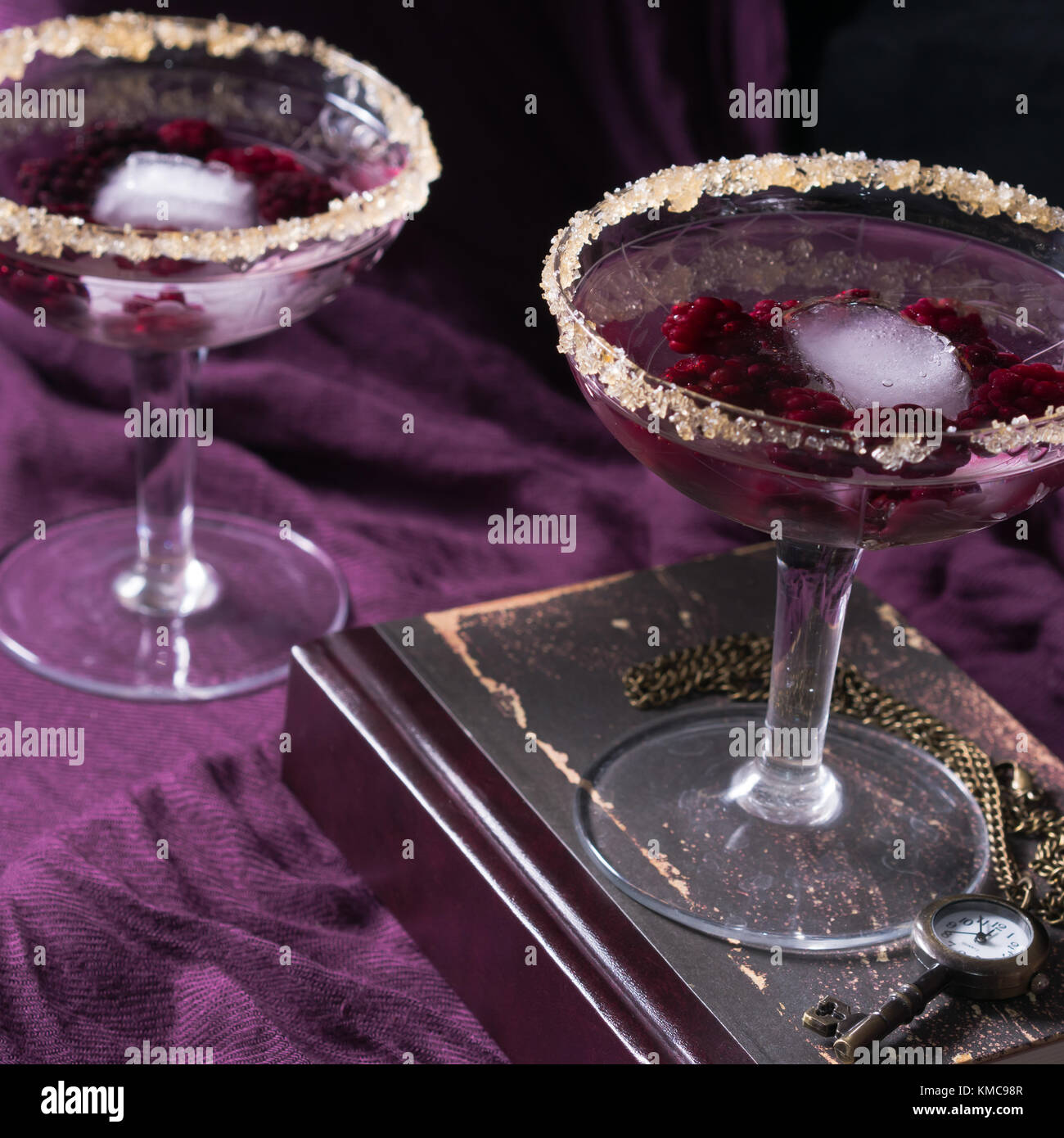 Two aperitif alcohol cocktails drinks with berries on purple background