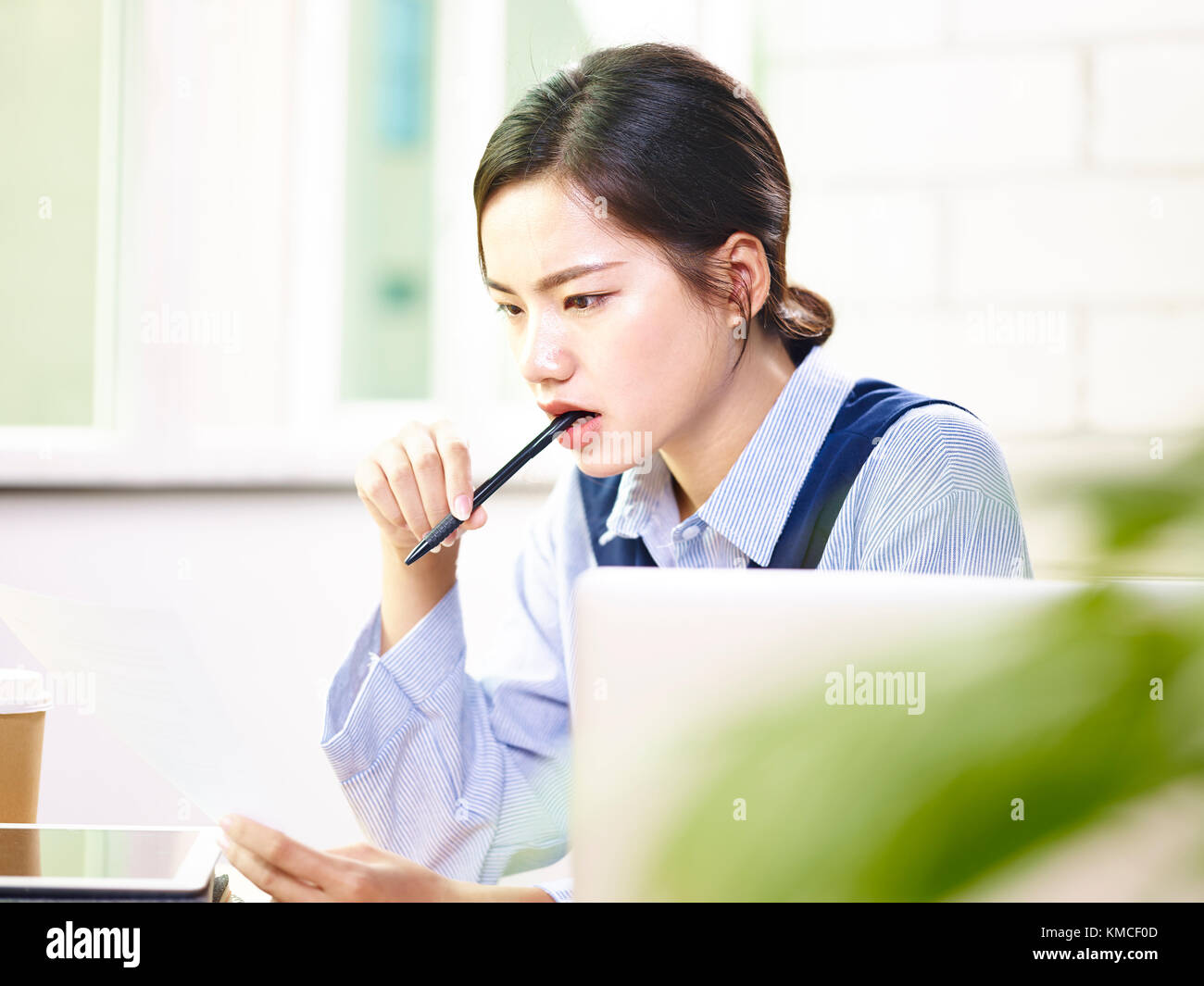 young asian woman corporate executive analyzing a report in modern office. Stock Photo