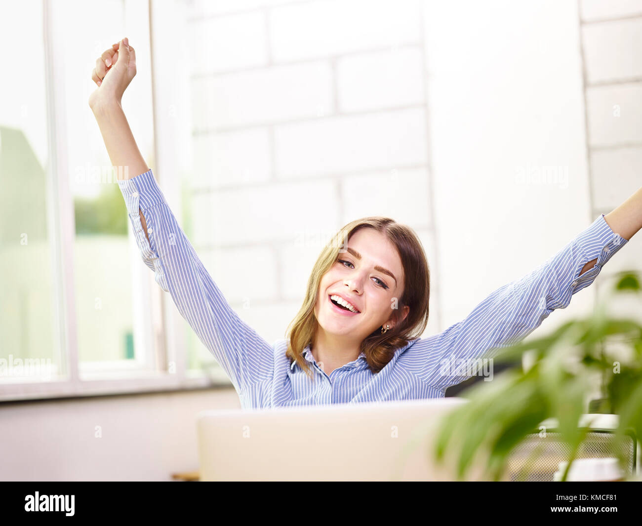 young caucasian business executive stretching arms in office celebrating completion of task. Stock Photo