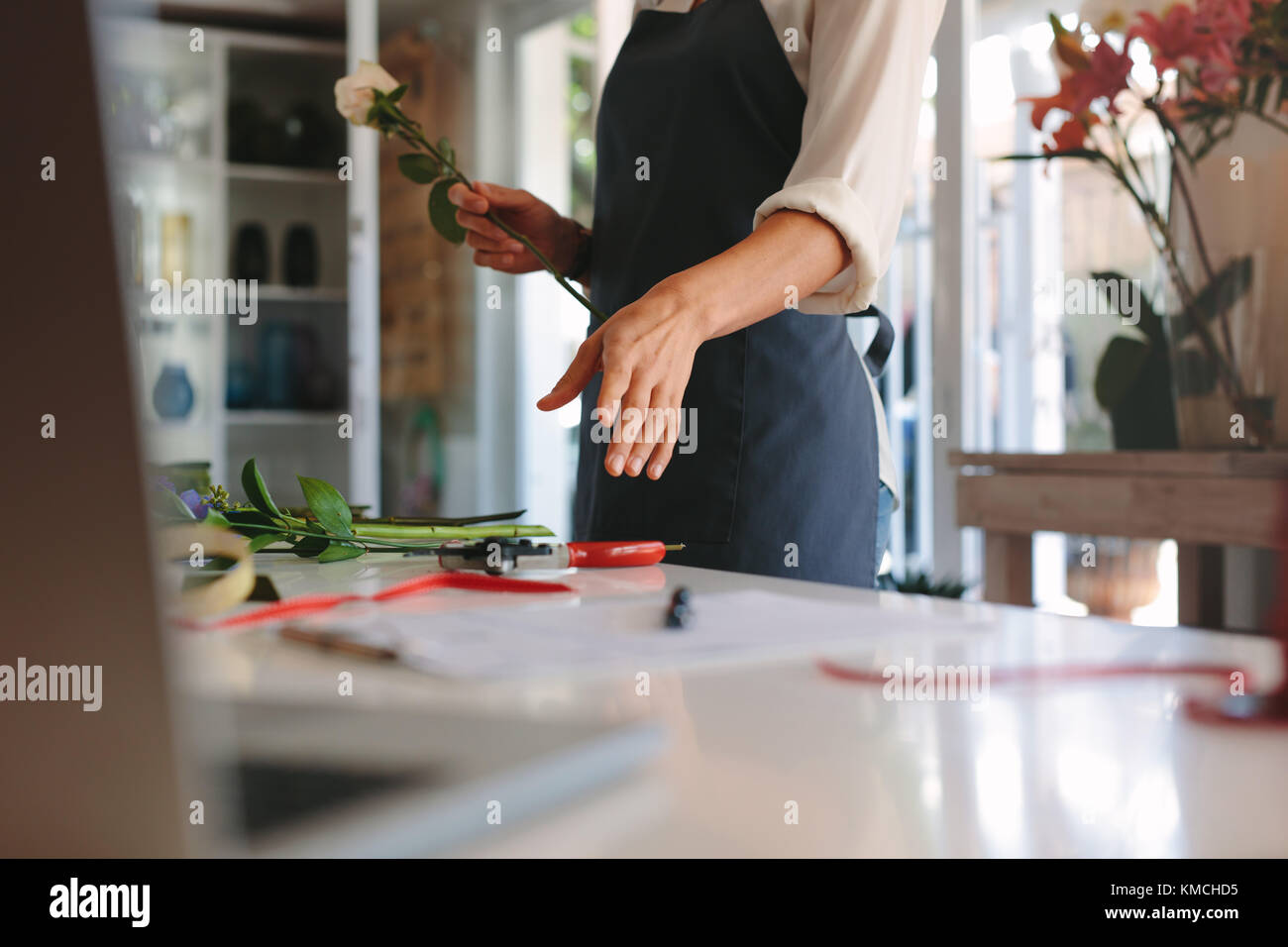 Hands of female working at flower shop arranging flowers. Woman florist making bouquet with flowers on counter. Stock Photo