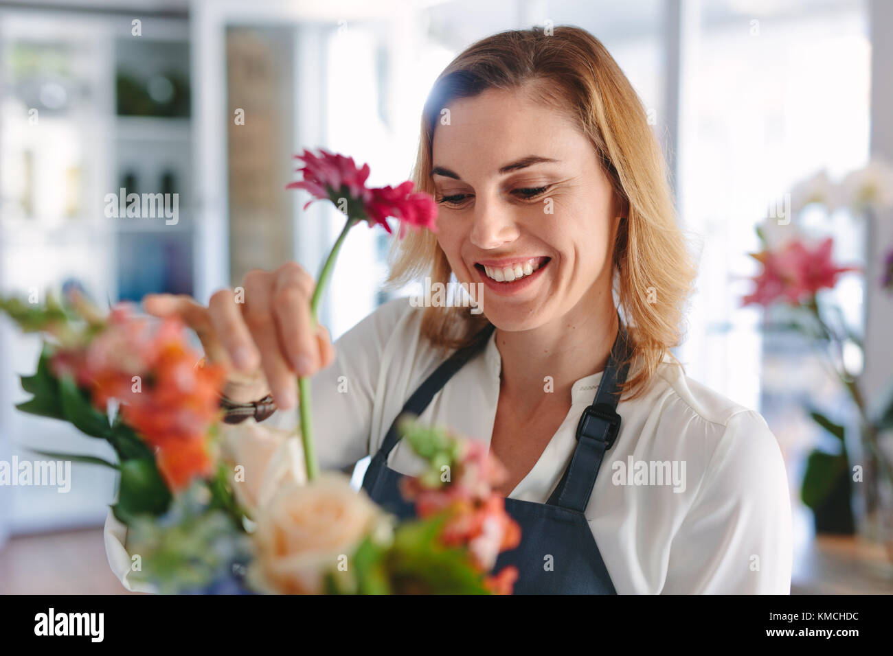 Female florist arranging flowers. Woman flower shop owner placing flowers in a bouquet. Stock Photo