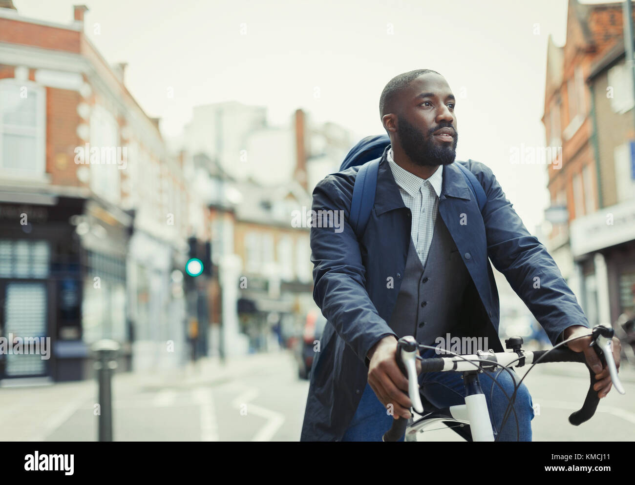 African businessman commuting, riding bicycle on urban street Stock Photo
