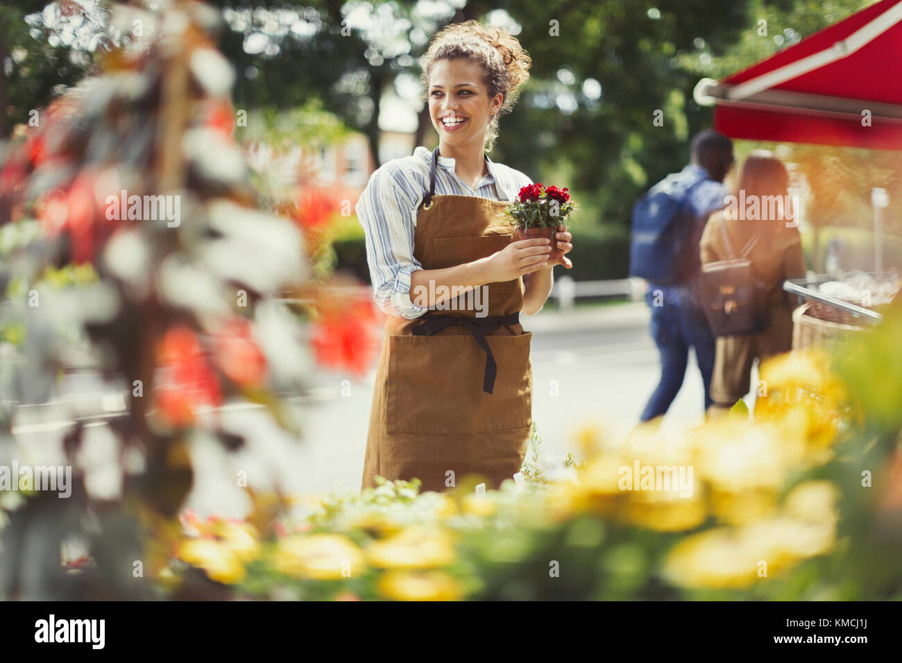 Smiling female florist working at flower shop storefront Stock Photo ...