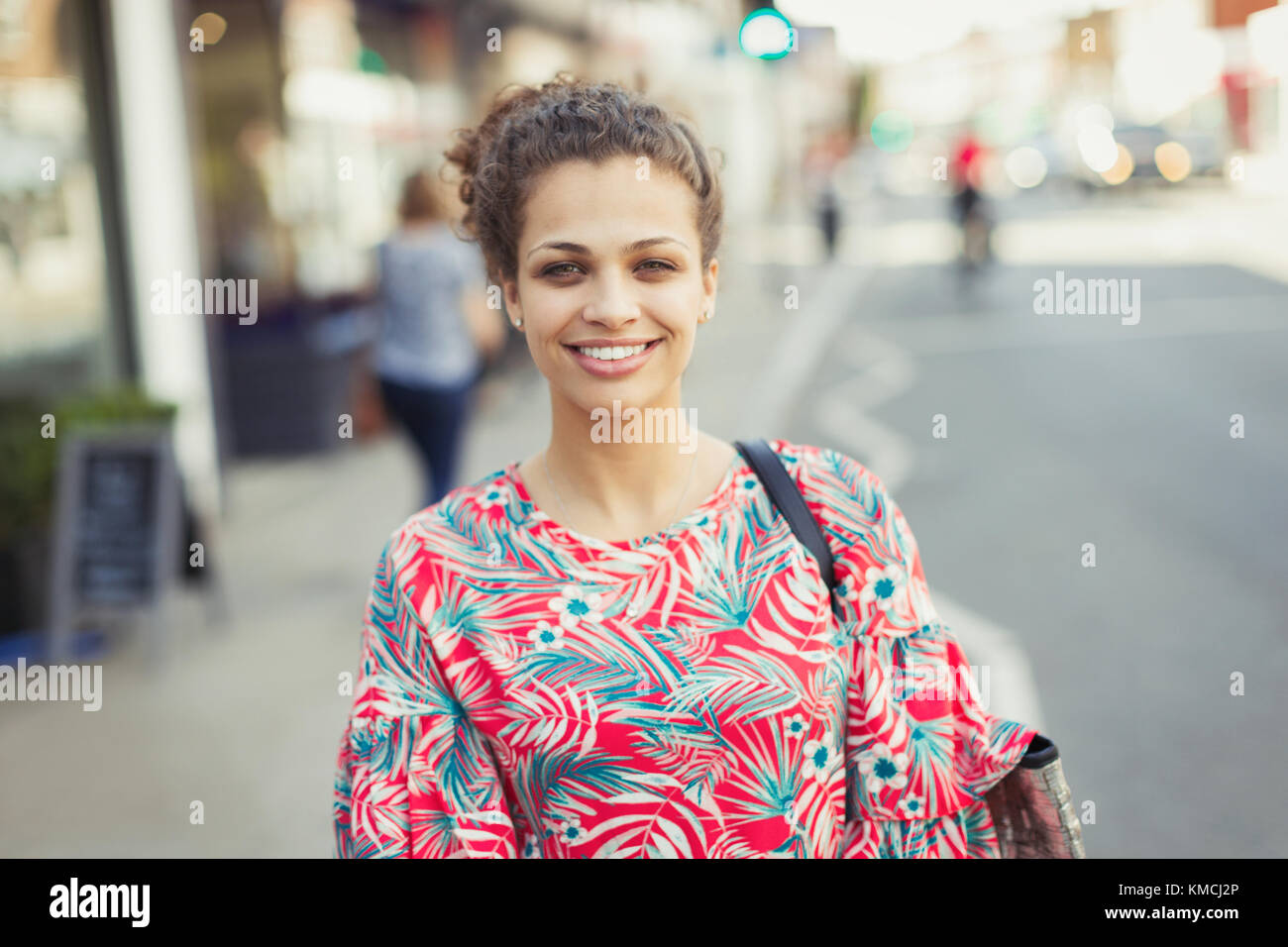 Portrait smiling young woman on urban street Stock Photo