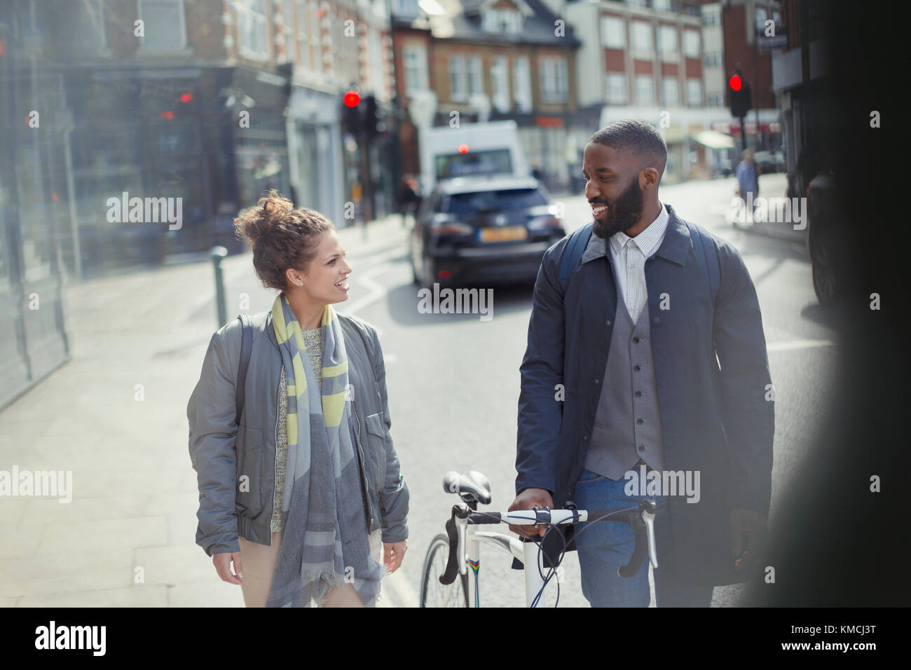 Couple walking, commuting with bicycle on urban street Stock Photo