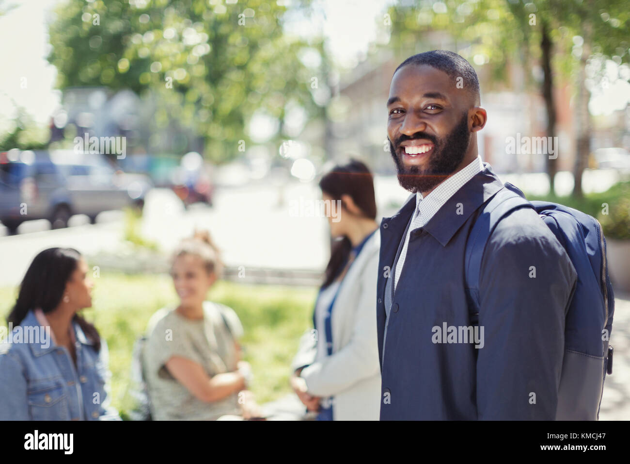 Portrait smiling businessman with backpack in urban park Stock Photo
