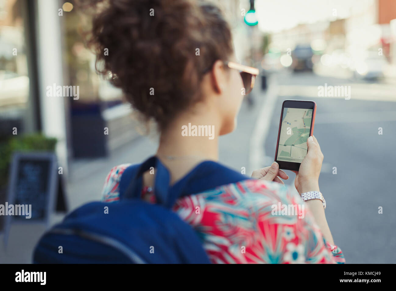 Young female tourist with backpack using GPS on smart phone on urban street Stock Photo