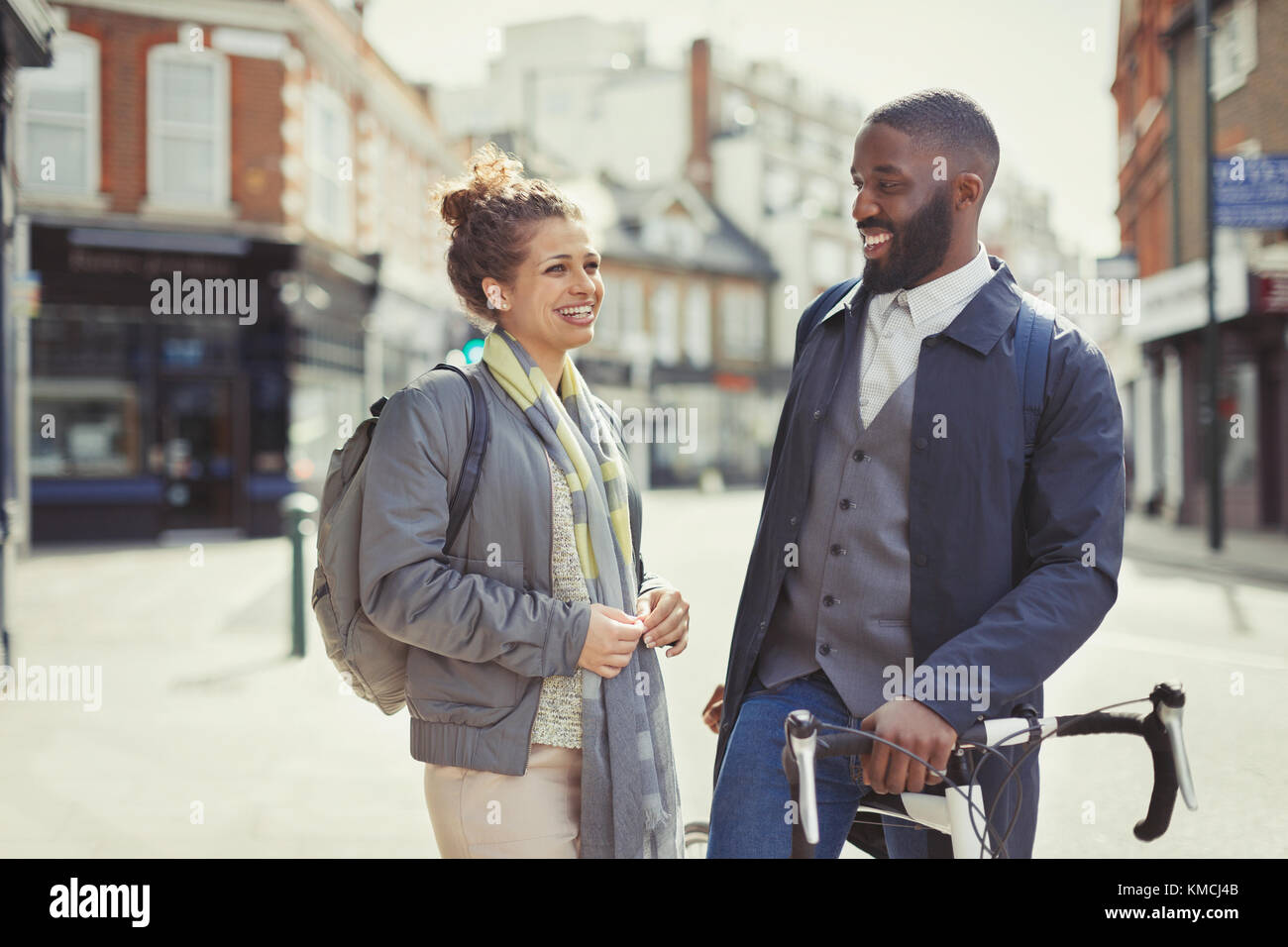 Smiling couple commuting with bicycle on sunny urban street Stock Photo