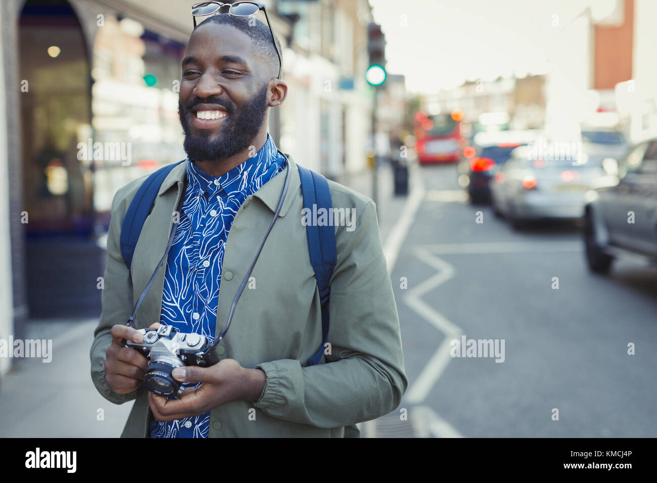 Smiling young male tourist with camera on urban street Stock Photo