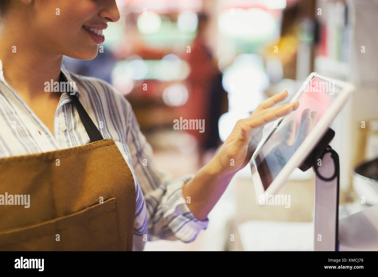 Female cashier using touch screen cash register in grocery store Stock