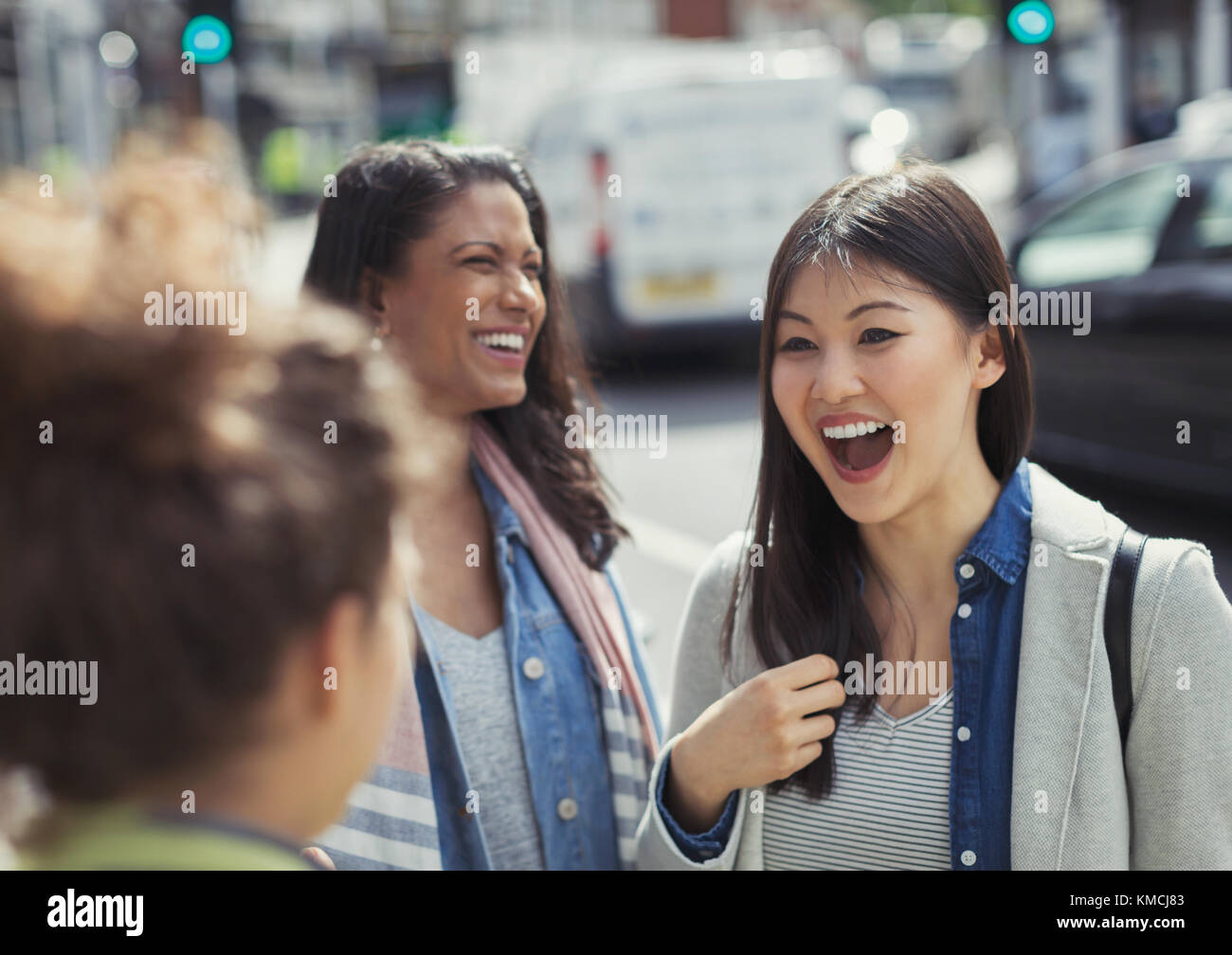 Female friends laughing on urban street Stock Photo
