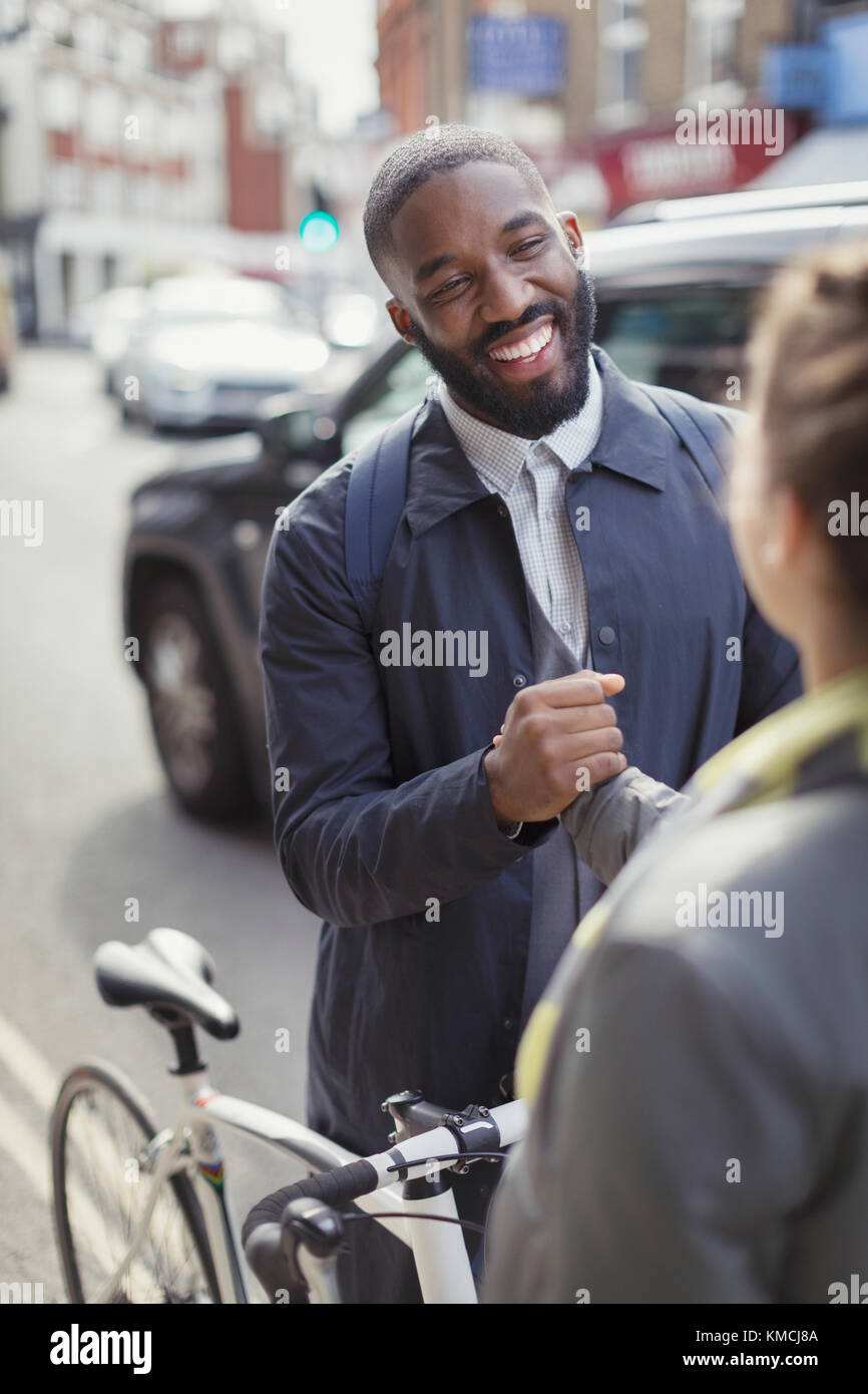 Smiling businessman with bicycle shaking hands with woman on urban street Stock Photo