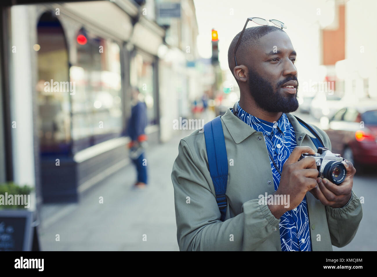 Young male tourist photographing with camera on urban street Stock Photo