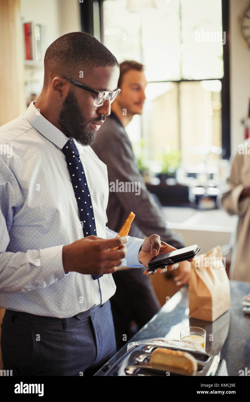 Businessman texting with smart phone in morning kitchen Stock Photo